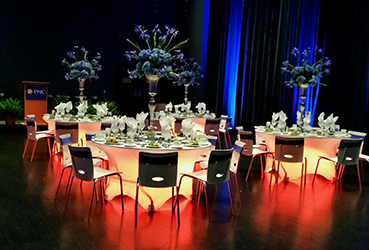 Reception tables set up with dramatic lighting on the Schuster Center stage