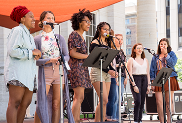 Young women on an outdoor stage singing