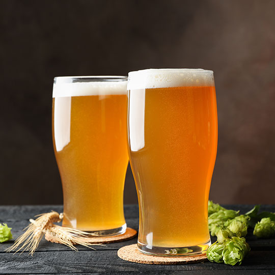 Beer on a table with wheat and hops